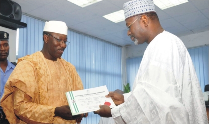 Chairman, Independent National Electoral Commission (INEC),  Prof Attahiru Jega (right) presenting certificate of return to Governor  Kayode Fayemi of Ekiti State in Abuja, on Monday
