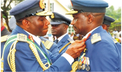 FRED10121101 President Goodluck Jonathan (left) decorating Chief of Air Staff, Air Marshal Mohammed Umar, with NAF Distinguished Flying Star medal and presentation of flag to Mobility Command in Abuja, yesterday