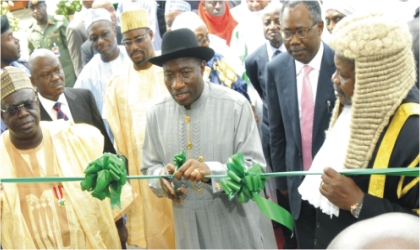 FRED21101103 President Goodluck Jonathan (middle) cutting the tape to inaugurate the new Federal High Court complex in Minna yesterday while Niger State Governor, Babangida Aliyu (left) and Chief Judge of Federal High Courts, Justice Ibrahim Auta (right) and Minister of Justice, Mohammed Adoke (SAN), watch