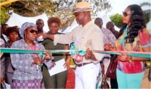 Representative of the wife of Rivers State Governor, and Commissioner for Women Affairs, Mrs Joeba West (left) cutting the tape with the assistance of her Commerce and Industry counterpart, Barr Chuma Chinye, at the opening of the 3rd Port Harcourt Xmas Discount Market in Port Harcourt , yesterday. Photo: Chris Monyanaga