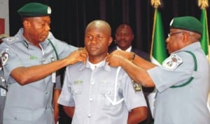 Comptroller-General of Customs, Alhaji Dikko Abdullahi (right) assisted by deputy Comptroller-General, Corporate and Support Services, Mr John Atte, decorating Assistant Superintendent, Hamza Musa, who bagged a special promotion for gallantry and excellent service, with his new rank in Abuja last Friday. Photo: NAN