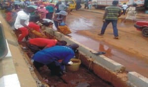 People scooping kerosene from the drainage at the scene of a tanker accident at Uselu in Benin-City, recently. Photo: NAN