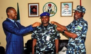 Enugu State Governor, Mr. Sullivan Chime (left), assisting State Police Commissioner, Mr. Mohammed Adamu (right) to decorate the Governor's Orderly, Mr. Anthony Embugus, recently promoted to the rank  of an Inspector recently.