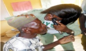 A youth corps member, Dr Trix-Meyi Omonigho, examining the eyes of a patient during a free medical outreach organized by corps members for residents of Ijah-Tampe community in Kwali Area Council of FCT, recently.