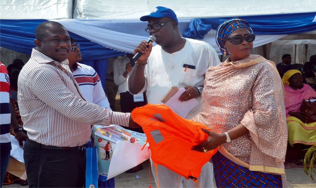 Managing Director, NIWA, Hajiya Tina Maryam Ciroma (right) presenting safety jackets to the Vice Chairman, Maritime Workers Union of Nigeria, Rivers State Council, Comrade, Godwin Dominic, during the 2014 NIWA Safety Awareness Campaign at Port Harcourt NIWA Dockyard, Marine Base last Wednesday. With her is NIWA General Manager, Corproate Affairs, Mr, Tayo Fadile. Photo: Nwiueh Donatus Ken