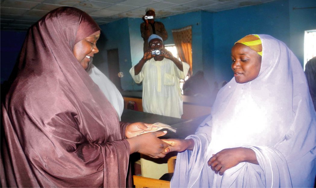 Wife of Dandume Local Government Chairman, Hajia Hadiza Ya'u Ahmad-noa (left), presenting cash empowerment support to one of the 50 physically challenged persons in Dandume, Katsina State recently.