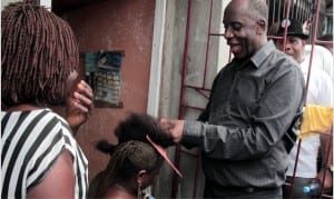 Leading by example: Rivers State Governor, Rt. Hon. Chibuike Rotimi Amaechi plaiting the hair of a woman as he convinces her to vote for the All Progressives Congress (APC), during his door to door campaign in Bonny Island, Rivers State, Wednesday.