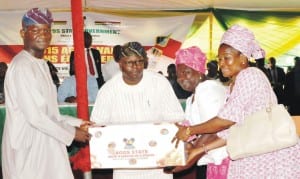 L-R: Governor Babatunde Fashola of Lagos State, assisted by Lagos State Commissioner for Agriculture, Prince Gbolaham Lawal in presenting agricultural  products to beneficiaries, Mrs Adenike Bolaji and Mrs Esther Abraham, at the 2015 Agric Value Chain Empowerment Programme in Lagos, yesterday.     Photo: NAN