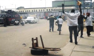 People rasing their hands in compliance with police order as they walk pass the scene of  a renewed clash between members of National Union of Road Transport Workers at Oshodi, in Lagos, recently.