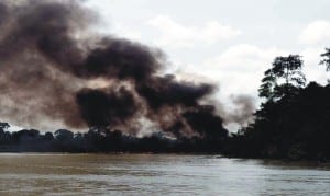 Thick smoke blowing from a burning vessel, following an operation of the Joint Task Force (JTF) agianst oil thieves in which boats and illegal refinery site at Ogboinbiri Community, Southern Ijaw Local Government Area of Bayelsa State were reportedly set ablaze, recently.       	    Photo: NAN