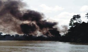 Thick smoke bellowing from a burning vessel, following an operation of the Joint Task Force (JTF) against oil thieves in which Boats and illegal refinery site at Ogboinbiri Community, Bayelsa State were  set ablaze, recently