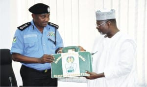 Independent National Electoral Commission (INEC) Chairman, Prof. Attahiru Jega (right), presenting INEC bag to the new IG, Mr Solomon Arase, during his first visit to INEC Headquarters in Abuja. recently.
