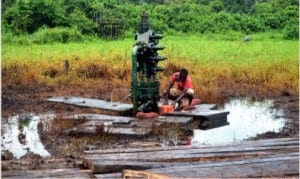 A resident fetching crude from residual crude oil leakage from Adebewa well 8 at Edagberi community, Ahoada West LGA in Rivers State on Monday