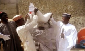 Acting Chairman, Head of Administration and Finance of Faskari LGA of Katsina State, Alhaji Sale Tsagero (right), helping a farmer with a bag of wheat seeds, during the launching and distribution of bags of wheat seeds, sprayers and multi-purpose water pumping machines to 31 groups of farmers under the Federal Government’s wheat farming support programme in Katsina State, recently.