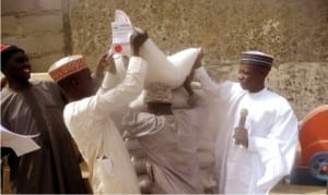 Acting Chairman, Head of Administration and Finance  of  Faskari  LGA  of  Katsina State,  Alhaji Sale Tsagero (right), helping a farmer with a bag  of  wheat seeds, during the launching and distribution of bags of  wheat seeds, sprayers and  multi-purpose water pumping machines to 31 groups of  farmers  under the Federal Government’s wheat  farming support programme in Katsina State, recently.