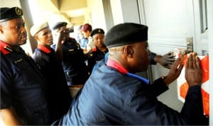  Head of private guard Companies,Nigeria Security and Civil Defence Corps, Plateau State Command, Mr Adeboye Popoola (right), with his men sealing off an illegal private security guard Company in Jos, on Tuesday 