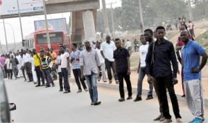 Stranded commuters at Lugbe Bus Stop as a result of fuel scarcity in Abuja on Friday last week.