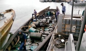 Officers of Nigerian Navy Ship (NNS), Pathfinder, Port Harcourt, guarding wooden boats loaded with 160 drums of illegally refined diesel which they siezed in Port Harcourt, recently.
