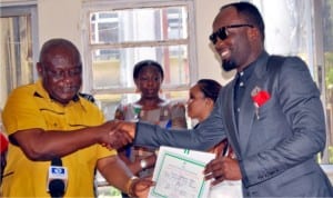Resident Electoral Commissioner for Rivers, Mr Aniedi Ikoiwak (left) presenting  Certificate of Return to Mr Kelechi Nwogu, representing Omuma Constituency in the State House of Assembly in Port Harcourt last Friday.